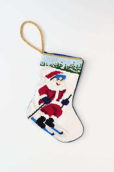 Christmas stocking featuring Santa skiing down a snowy hill with a red outfit against a snowy background