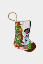 Needlepoint stocking with a girl holding a nutcracker beside a Christmas tree and presents