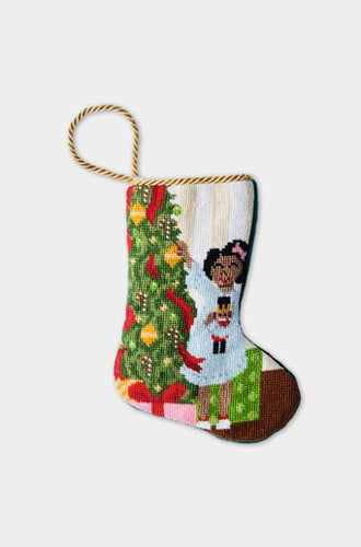 Needlepoint stocking with a girl holding a nutcracker beside a Christmas tree and presents